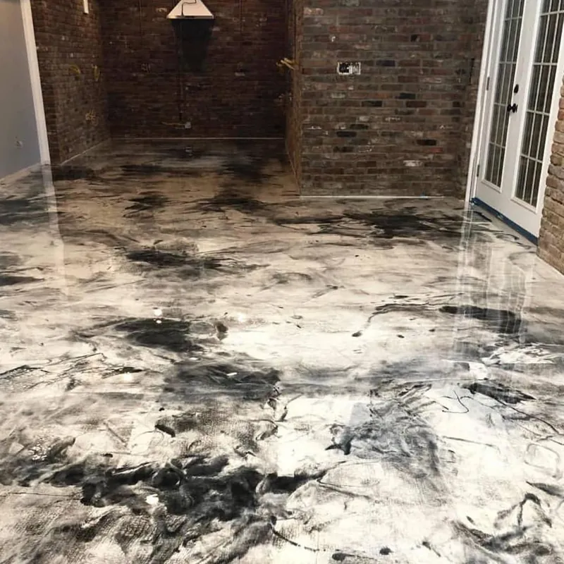 High-gloss white and black marbleized epoxy flooring in a brick-walled room.